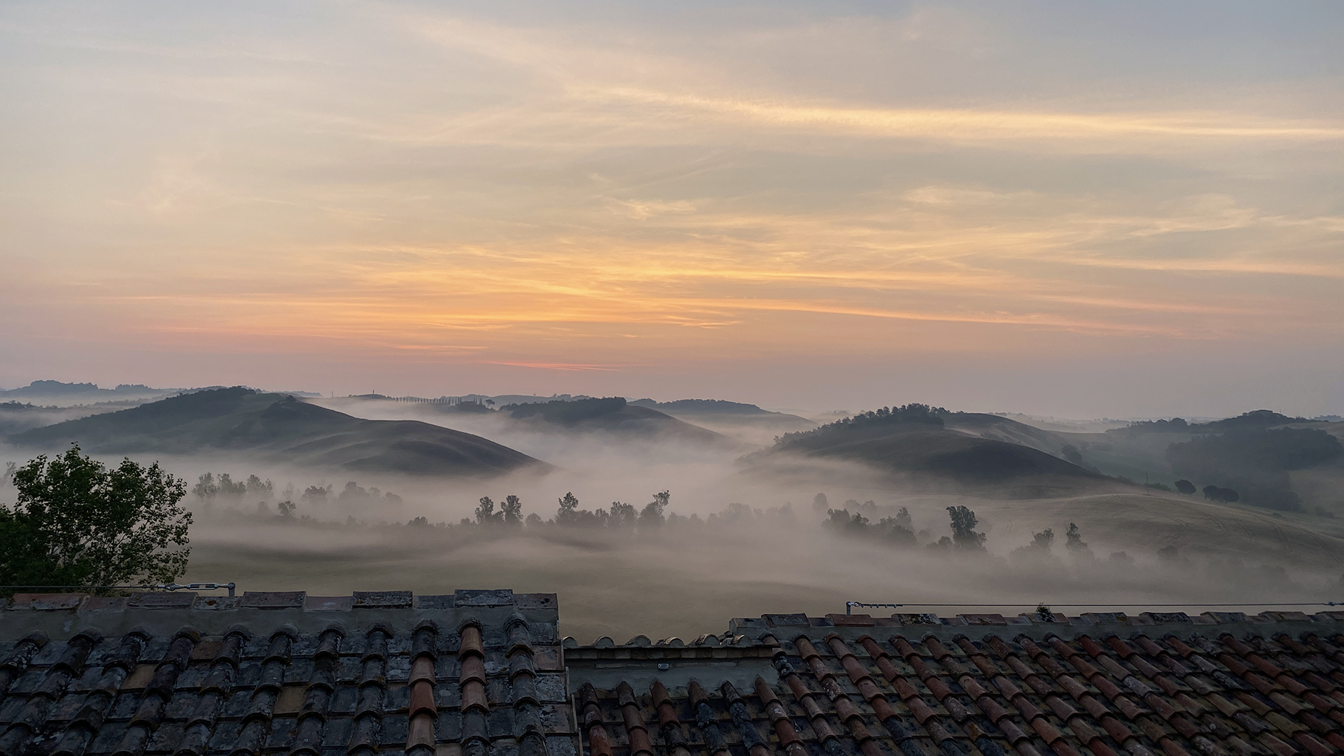 View of Tuscan countryside on a foggy day at sunrise from luxury hotel in Siena